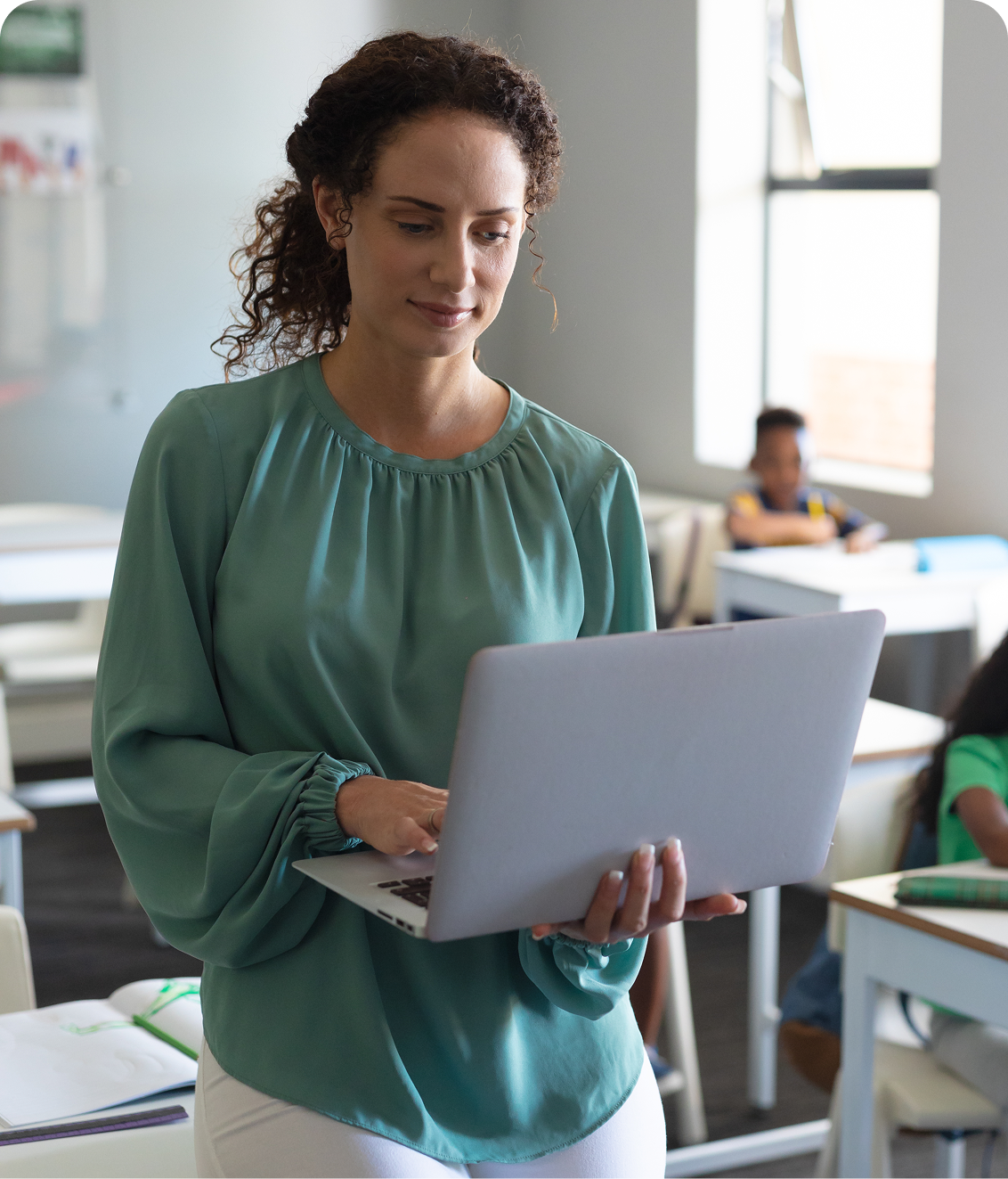 joven maestra caucasica usando una computadora portatil con estudiantes primarios multirraciales en el fondo 1